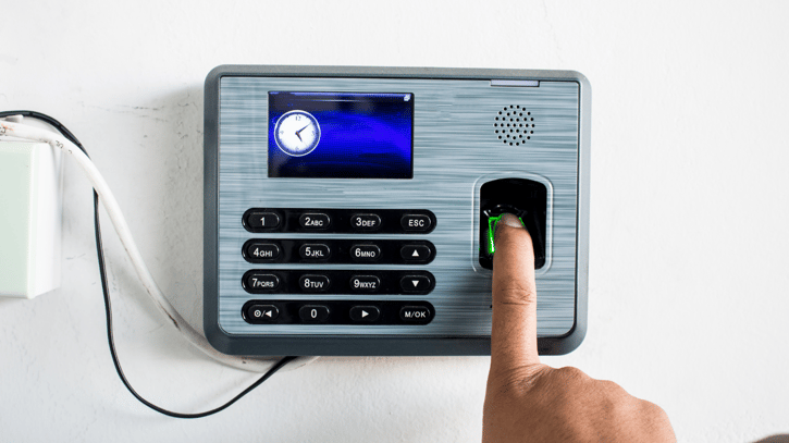 Finger of employee using biometric timekeeping system to clock into work