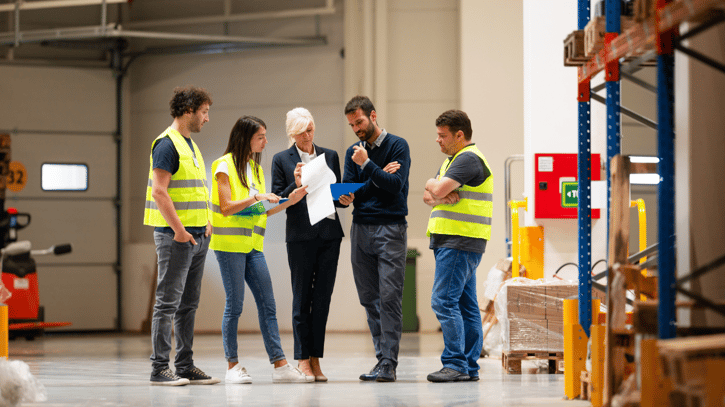 HR manager briefing warehouse staff on rota changes and shift premium for a night shift team.