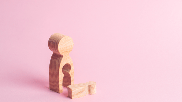 Wooden woman figure with a void from where a child fell, symbolising miscarriage or reproductive loss 