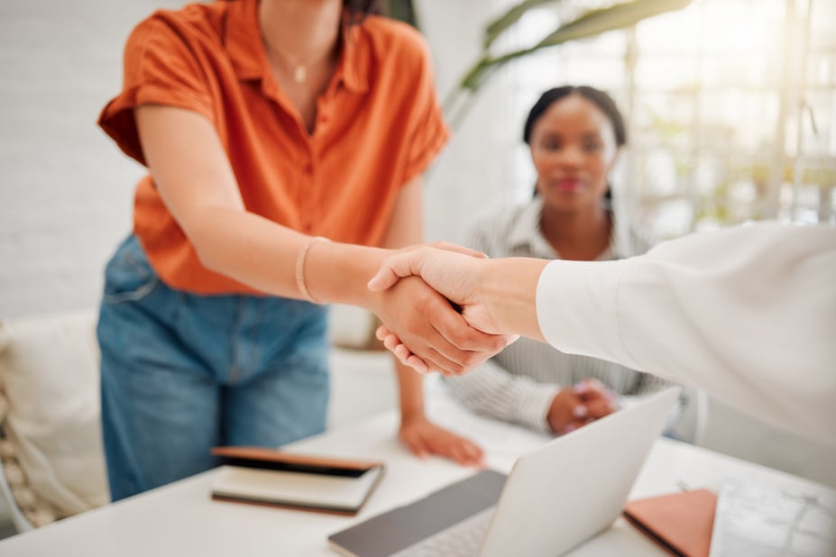 Businesswoman shaking hands with a new hire in an office - employee onboarding concept.